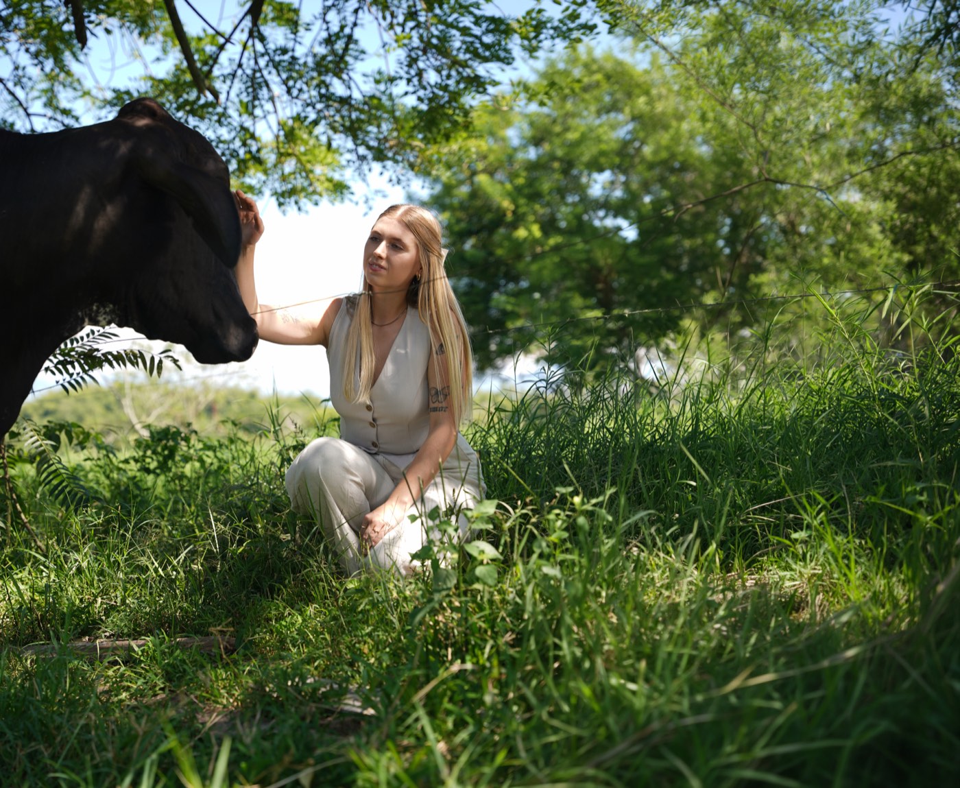 Ganadera sentada en el pasto junto a una vaca
